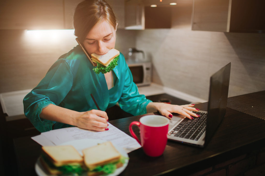 Girl with sandwhich in mouth, at computer, taking notes, Platinum Resumes, Kansas City, MO