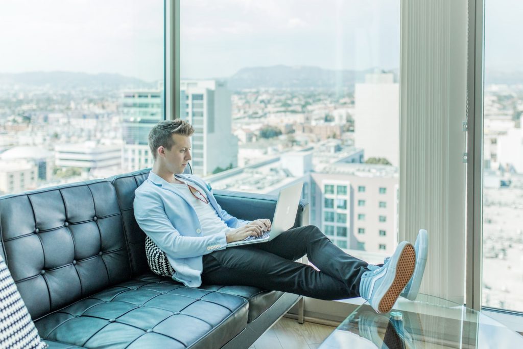 Man in highrise, on black leather couch, on laptop, Platinum Resumes, Kansas City, MO