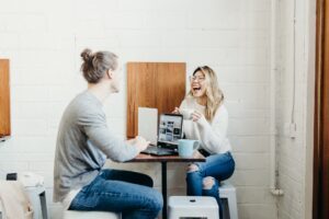 2 girls across from one another on laptops drinking coffee, Platinum Resumes, Kansas City, MO