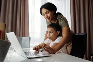 Child on laptop, mother behind helping, Platinum Resumes, Kansas City, MO
