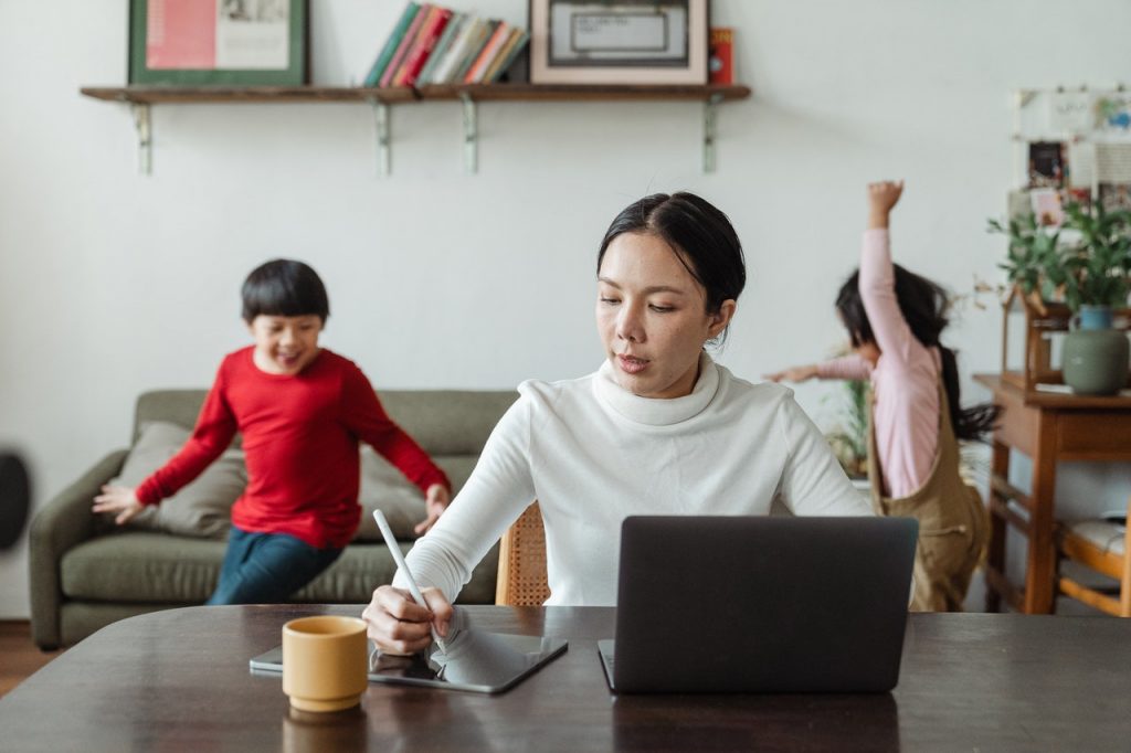 Woman working on resume at laptio with 2 kids in background, Platinum Resumes, Kansas City, MO