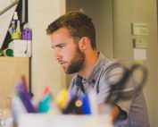 Young man with beard in room looking for job on computer, Platinum Resumes, Kansas City, MO