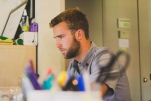 Young man with beard in room looking for job on computer, Platinum Resumes, Kansas City, MO