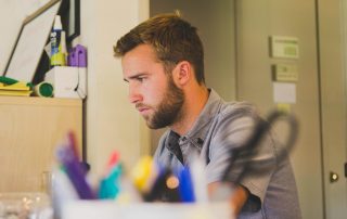 Young man with beard in room looking for job on computer, Platinum Resumes, Kansas City, MO