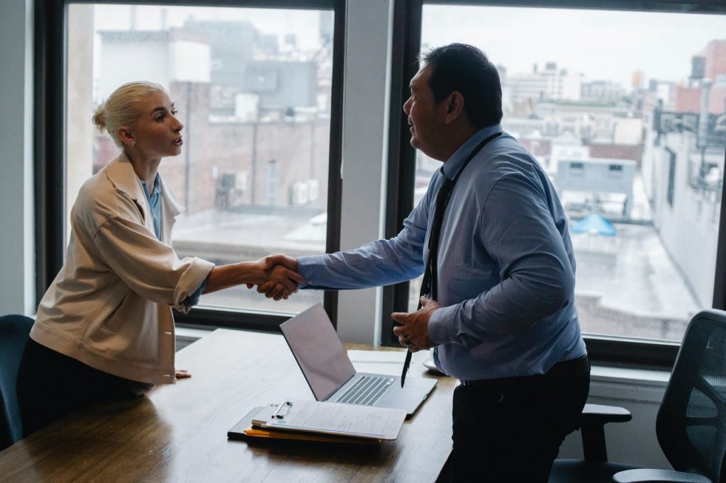 Man behind desk shaking hands with woman in a bun, Platinum Resumes, Kansas City, MO